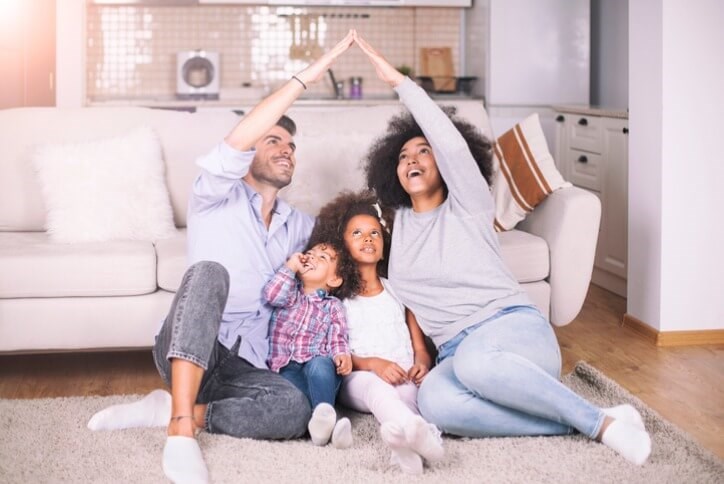 A young family of four sitting on the floor