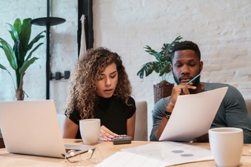 A couple budgets together in front of an open laptop and paperwork