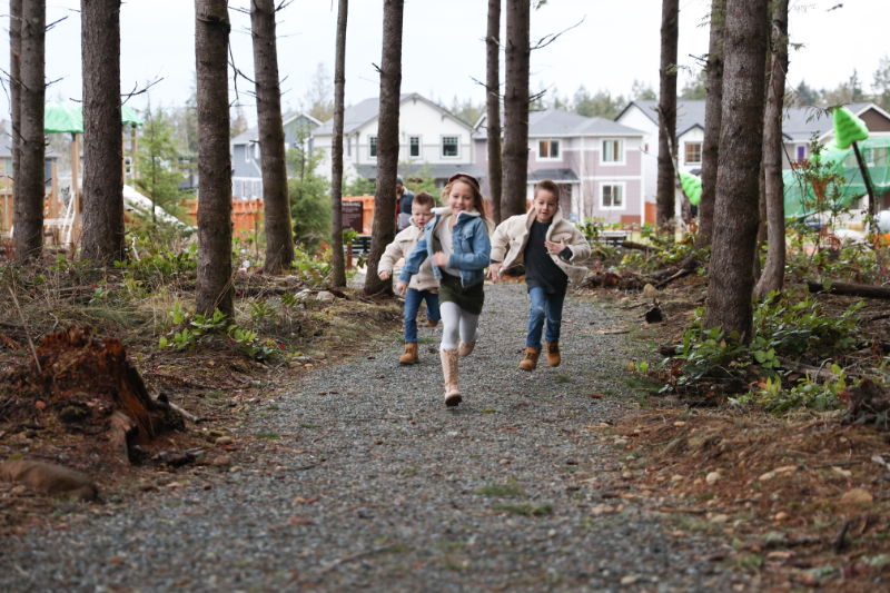 A group of kids running through a Tehaleh trail on a rainy day