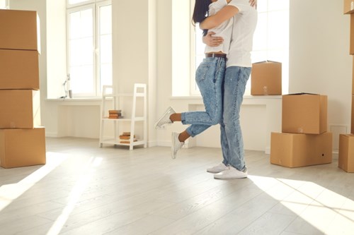 A couple in an embrace surrounded by moving boxes